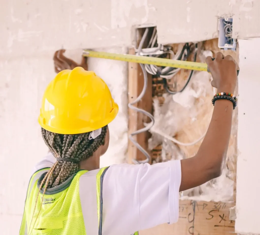 Contractor installing rigid foam insulation boards between wall framing members.